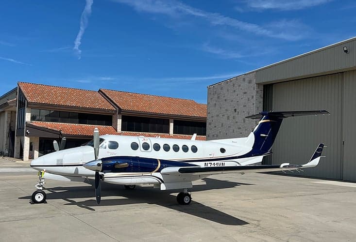 King Air aircraft N711VN parked on the tarmac in front of a hangar.