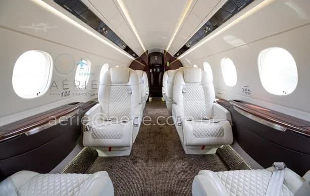 A slightly wider view of the aircraft's main cabin, showcasing the white quilted seats and large windows.