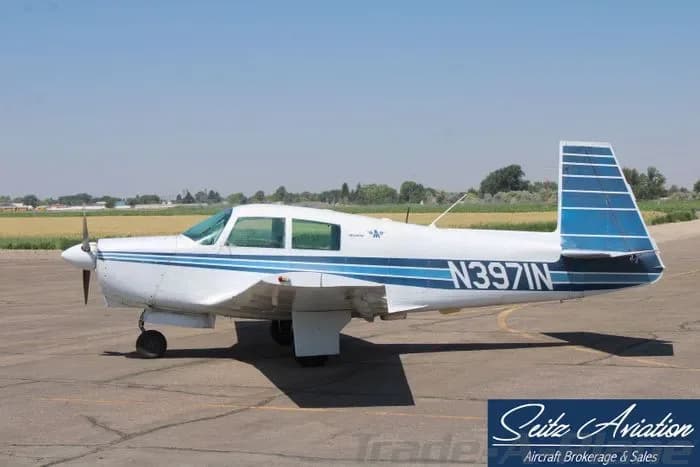 A white and blue Piper Cherokee parked on the tarmac.