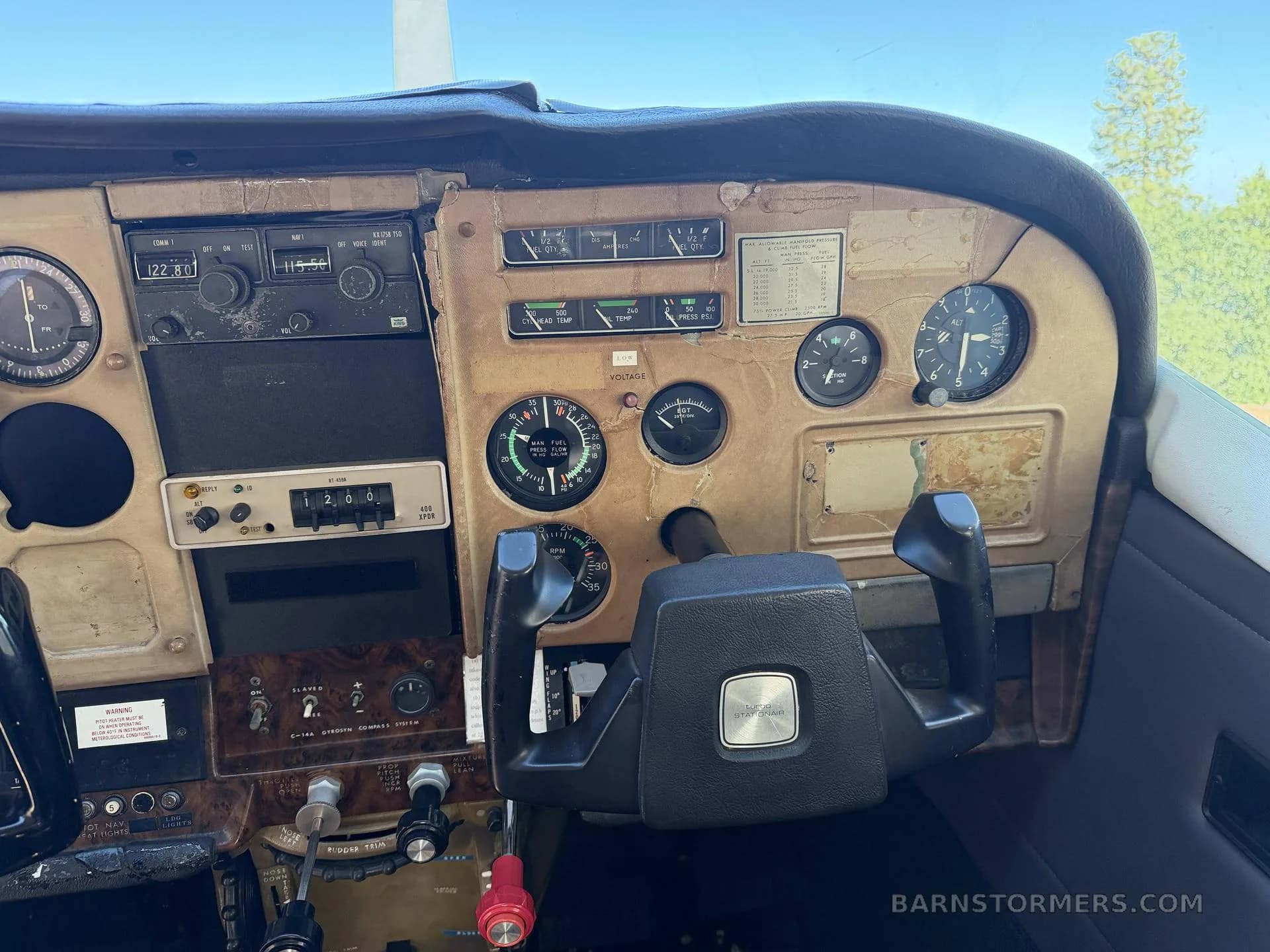 A close-up view of an aircraft's instrument panel with various gauges, radios, and a control yoke.