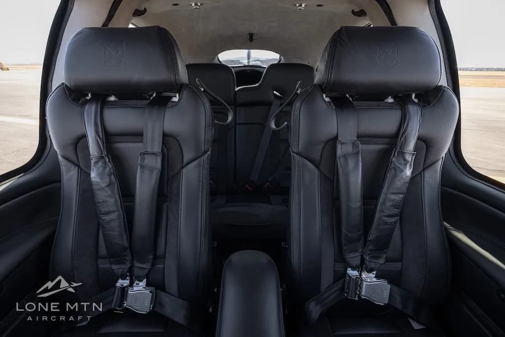 The black leather front seats of the aircraft cabin, showing seatbelts and headrests.