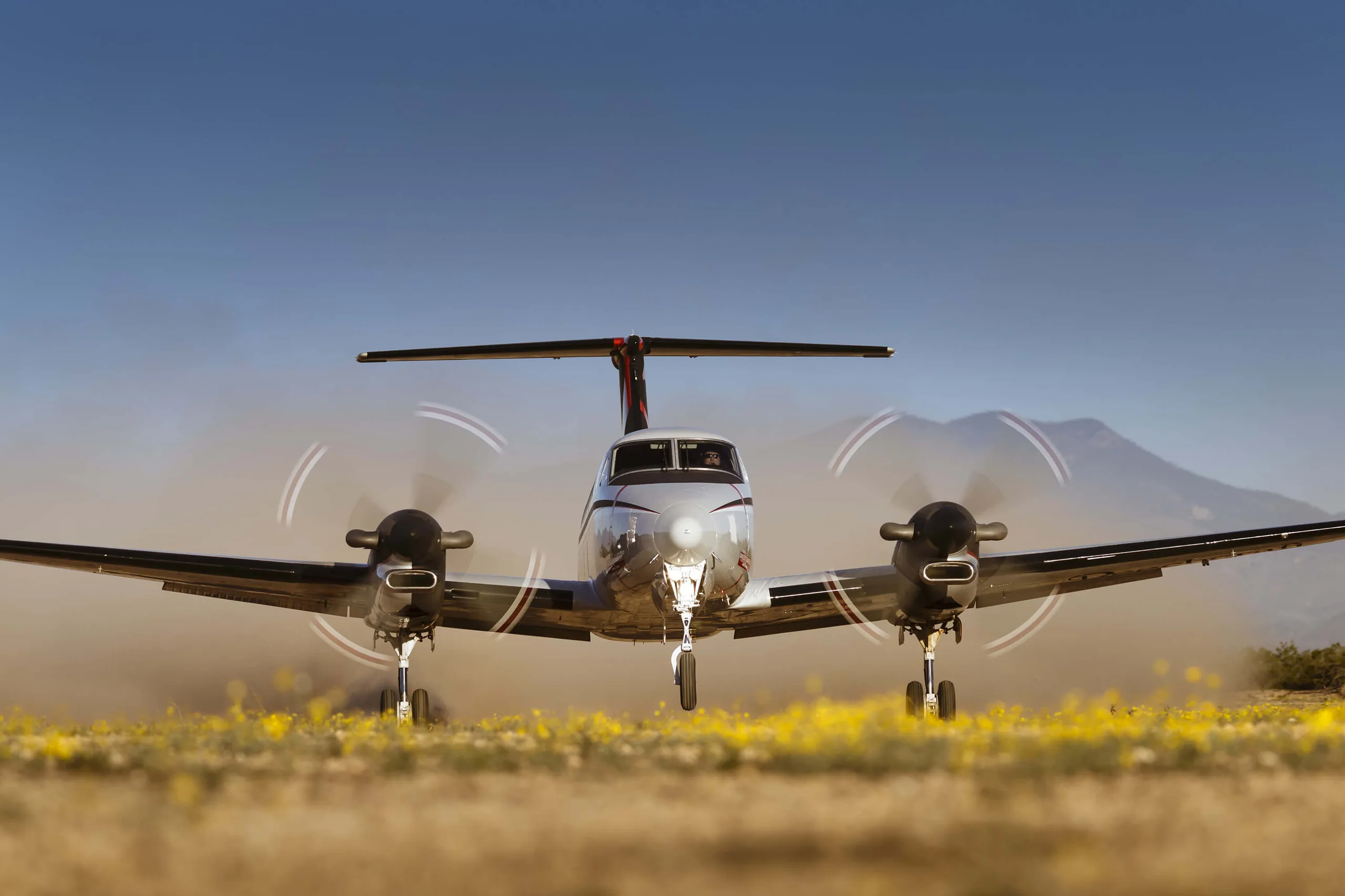 Front view of a King Air 350 taking off from a field of flowers.