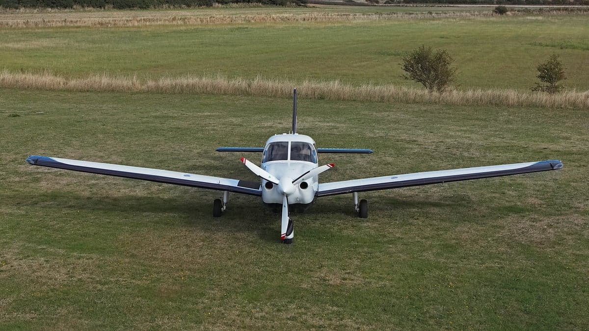 Front view of a white and blue aircraft on a grassy field.