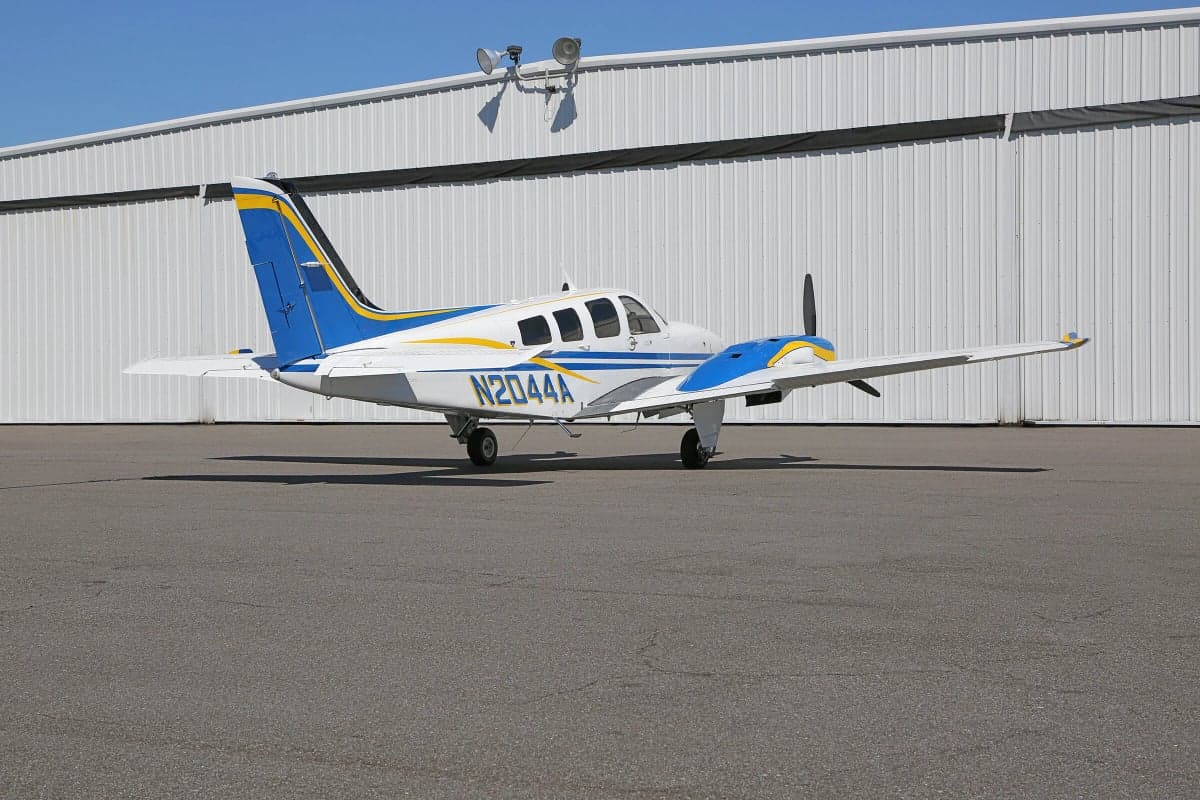 Side view of a Piper PA-31 Navajo Chieftain aircraft with registration N2044A parked on the tarmac in front of a hangar.