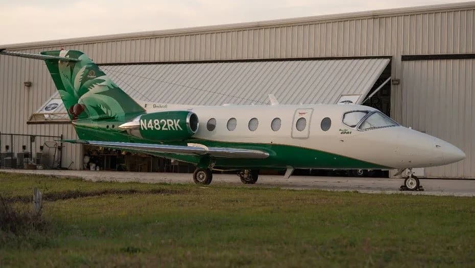 Beechcraft Premier 400A aircraft parked in front of a hangar with a green and white paint scheme.