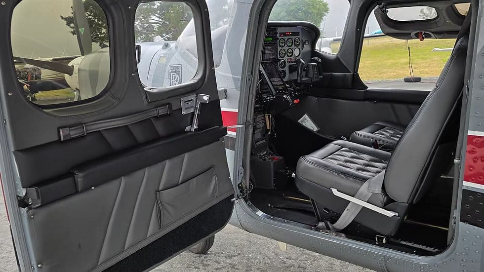 View of the Cessna Caravan's interior, showing the cockpit and passenger seats with the door open.