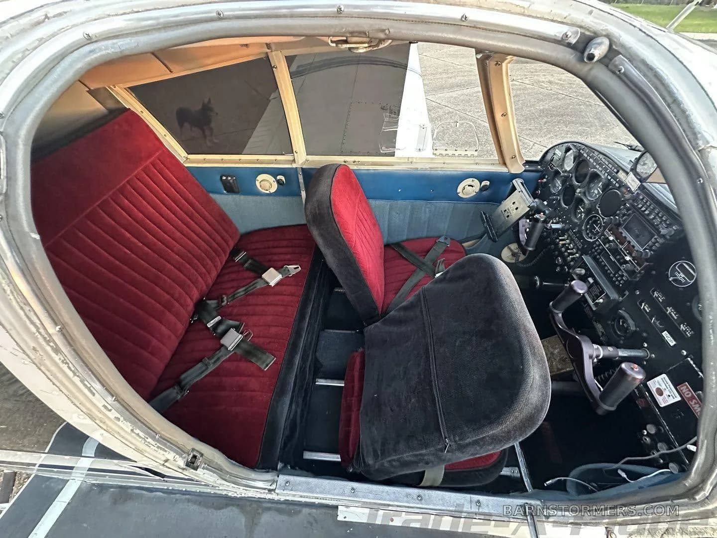 The aircraft's interior showing red velvet seats and a partial view of the instrument panel.