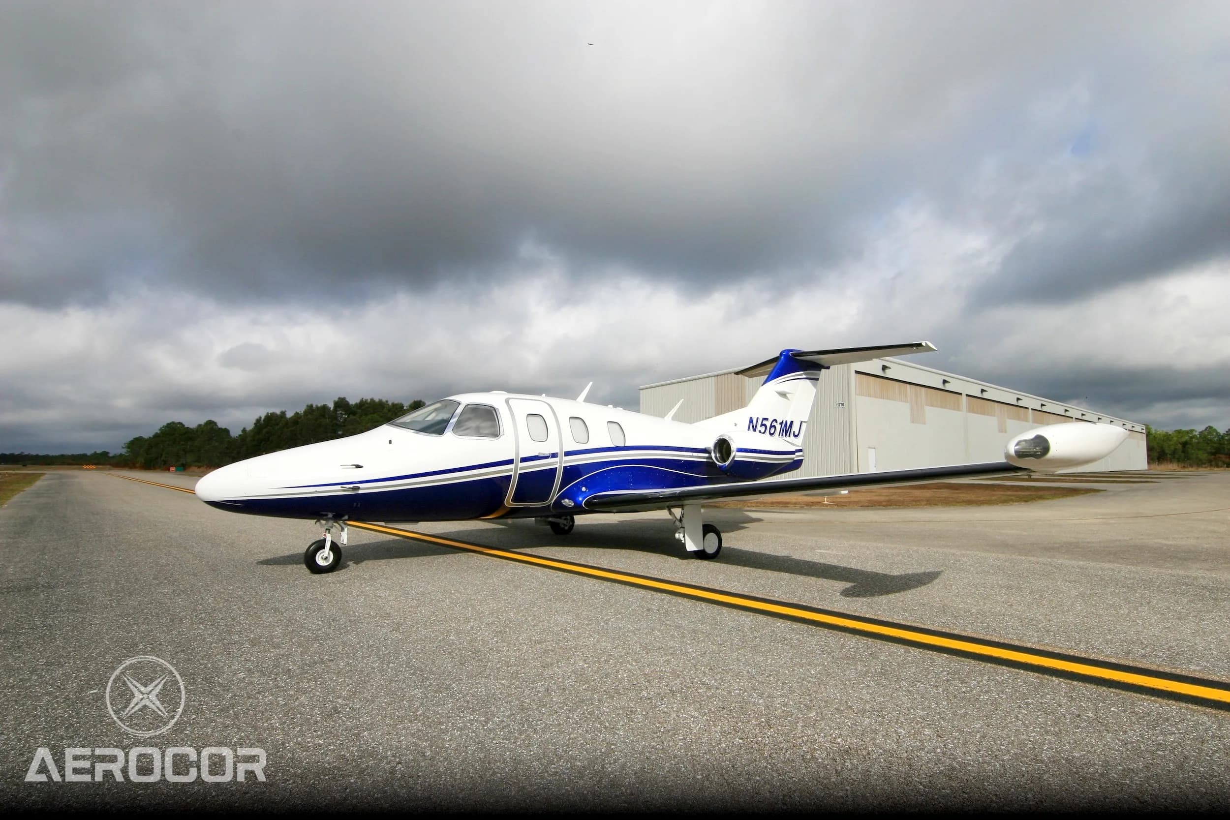 Side view of a white and blue Eclipse 500 jet, registration N561MJ, parked on an airfield.