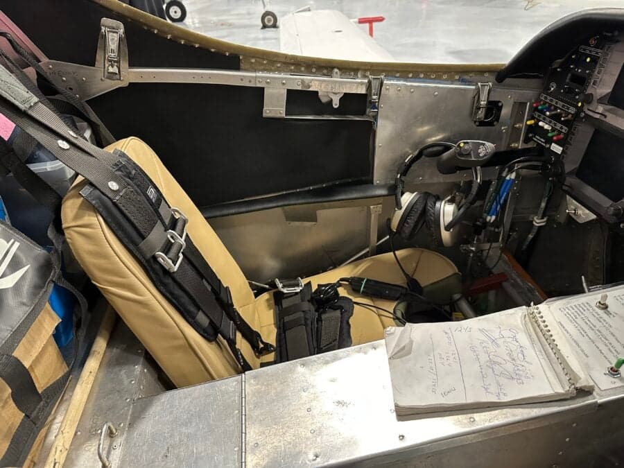 The interior of an aircraft with a seat, headset, and notepad.