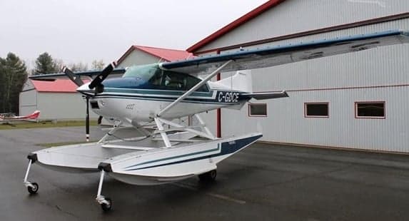 Cessna 206 on floats parked in front of a hangar.