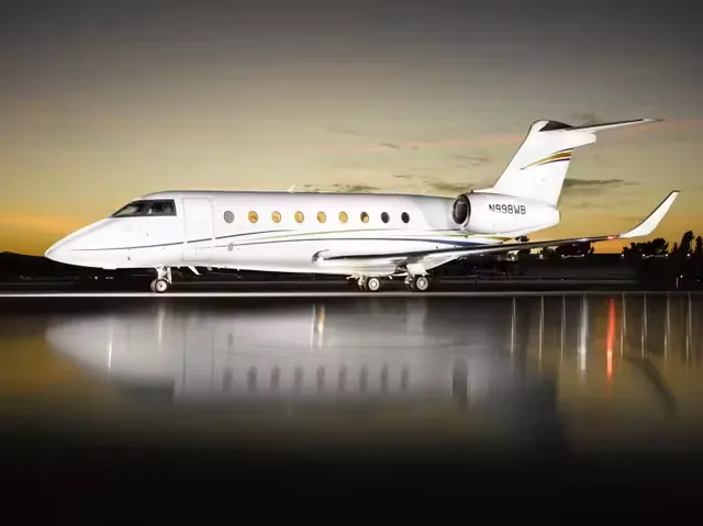 A Bombardier Global Express business jet on the tarmac at dusk, side view.