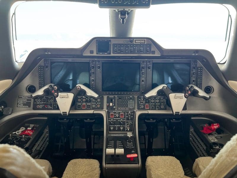 The Phenom 100 aircraft's cockpit features a modern instrument panel and controls.