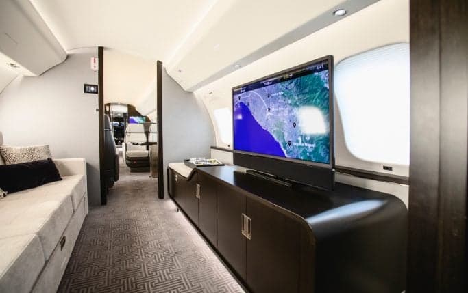 Bedroom area inside the Global 7500 cabin with a bed and side table.
