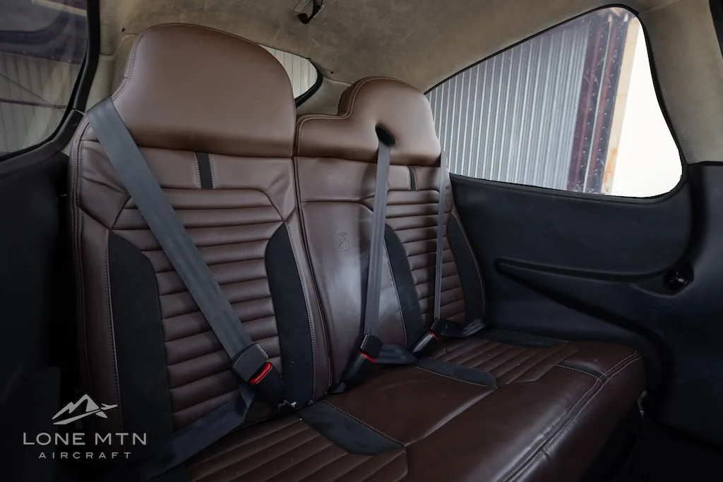 Brown leather rear passenger seats with seatbelts inside the aircraft cabin.