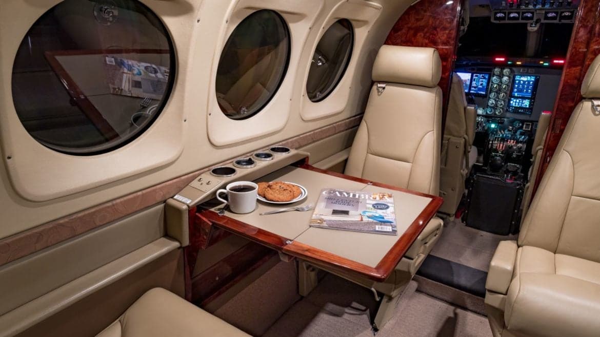 Interior view of the aircraft cabin with a table, seats, and cockpit visible.