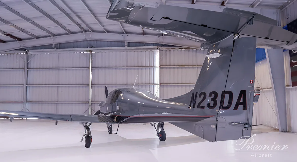 The tail of a gray Diamond DA62 aircraft with the registration number N23DA is visible in a hangar.