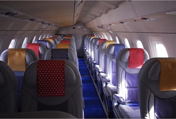 Interior view of aircraft cabin with blue carpet and colorful seat covers.