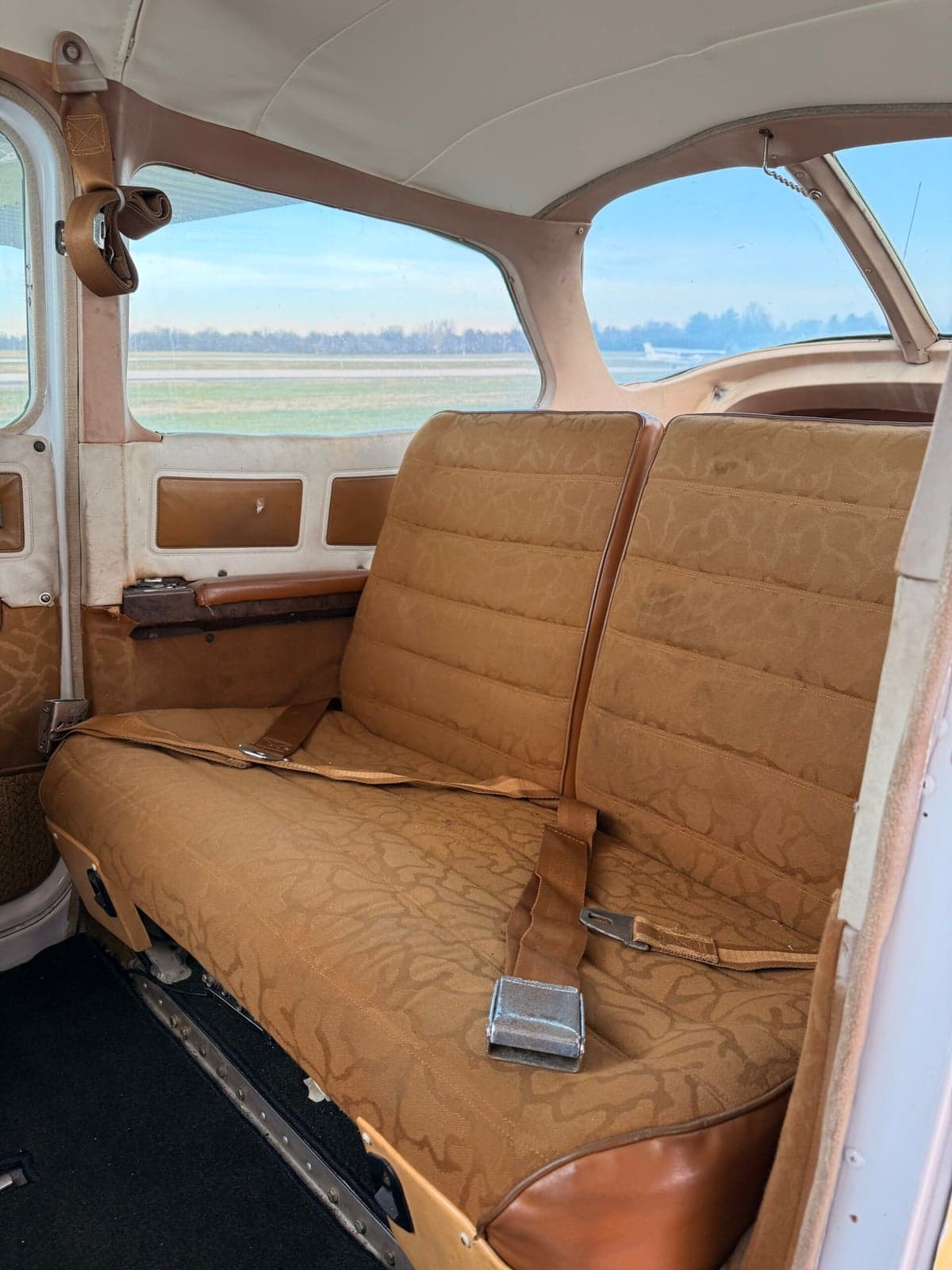 Rear bench seat of the Cessna 172 aircraft with brown patterned upholstery.