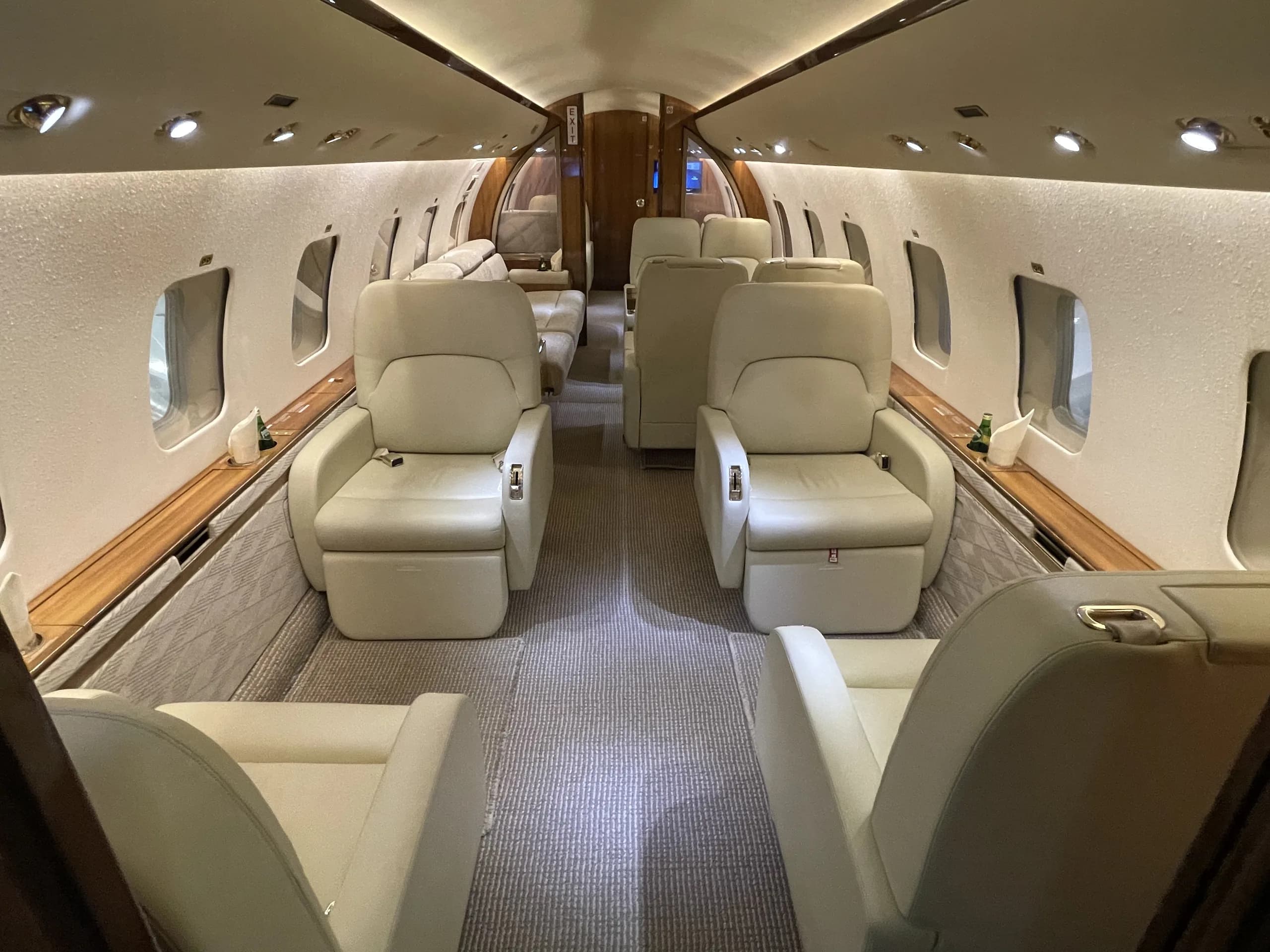 The luxurious interior cabin of a private jet with light-colored leather seats arranged in a club configuration.