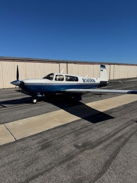 Side view of the N140RM aircraft on the tarmac in front of a hangar.