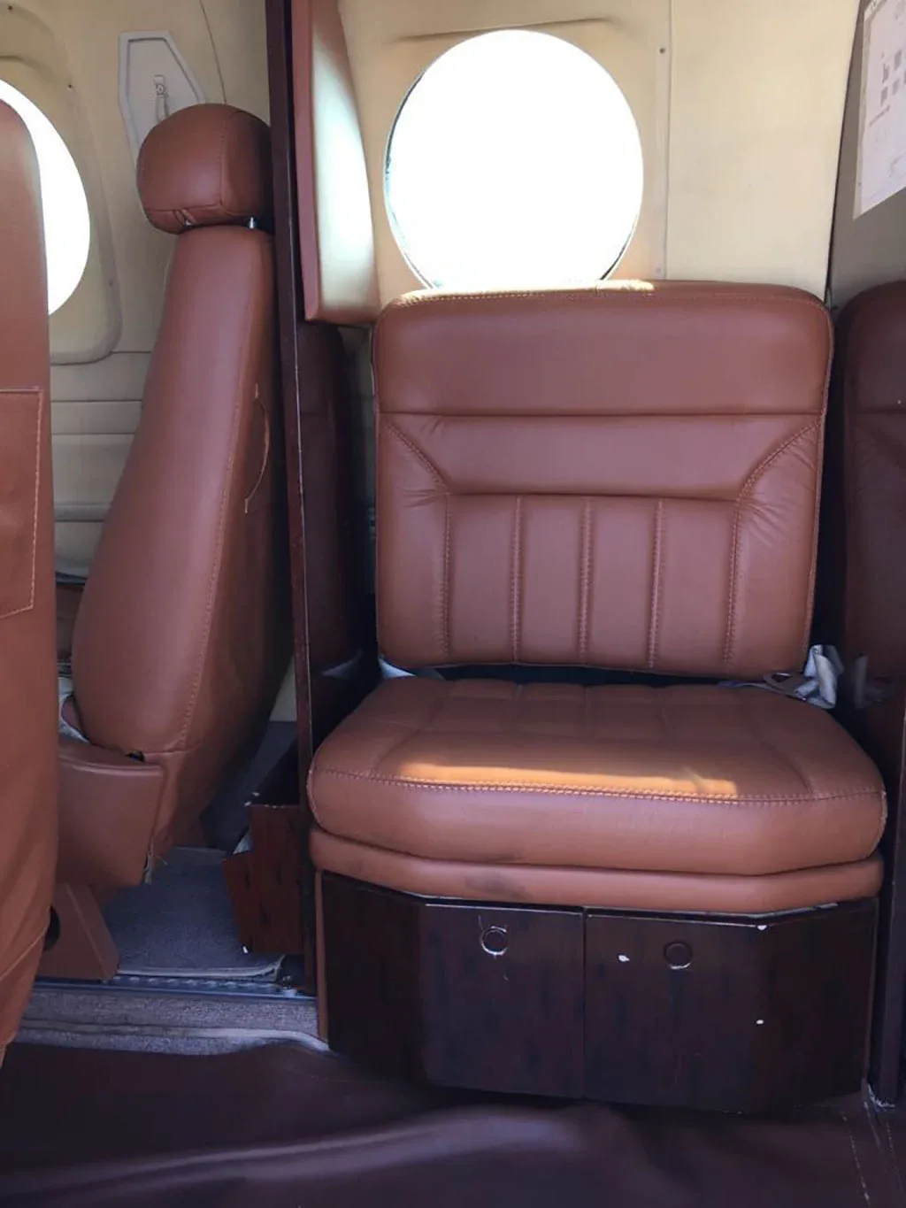 A close-up view of a brown leather passenger seat inside an aircraft cabin.
