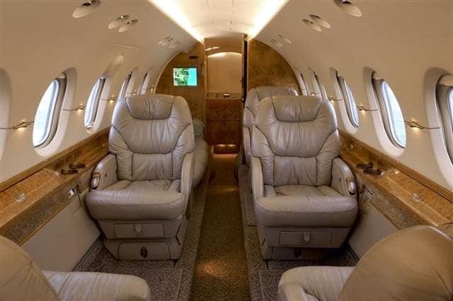 The aircraft's interior features leather seats and wood trim.