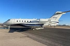 A white and blue private jet parked on a runway.