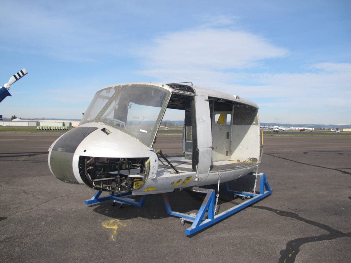 Helicopter fuselage on a blue stand at an airport.