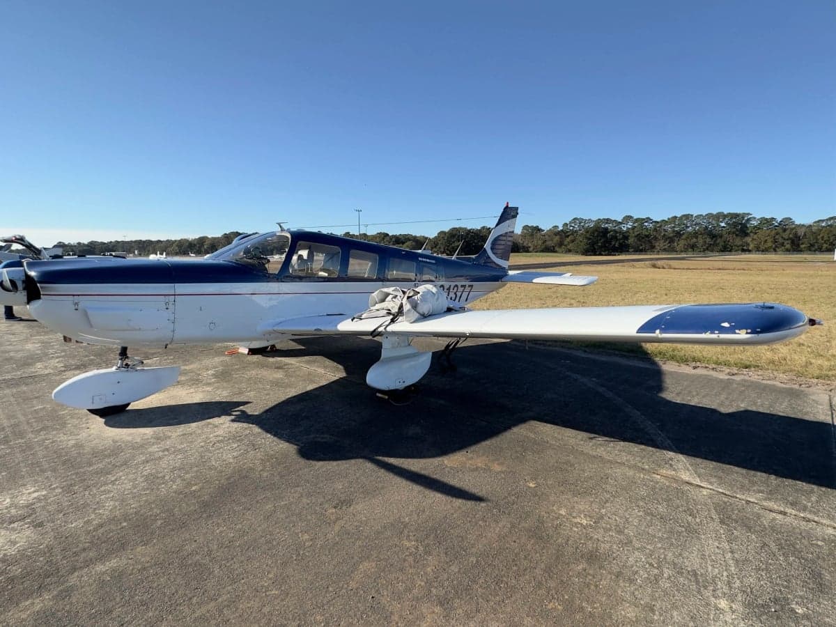 Side view of a blue and white Piper Cherokee aircraft with registration N31377.
