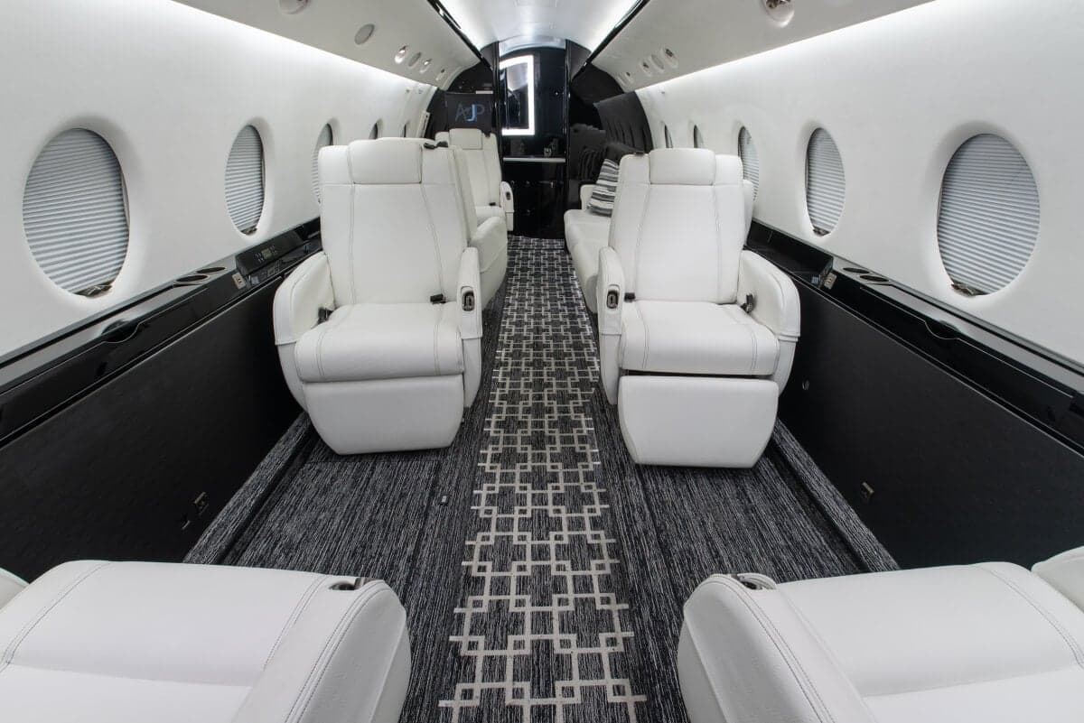 View of the aircraft's interior with white leather seats and a patterned carpet.