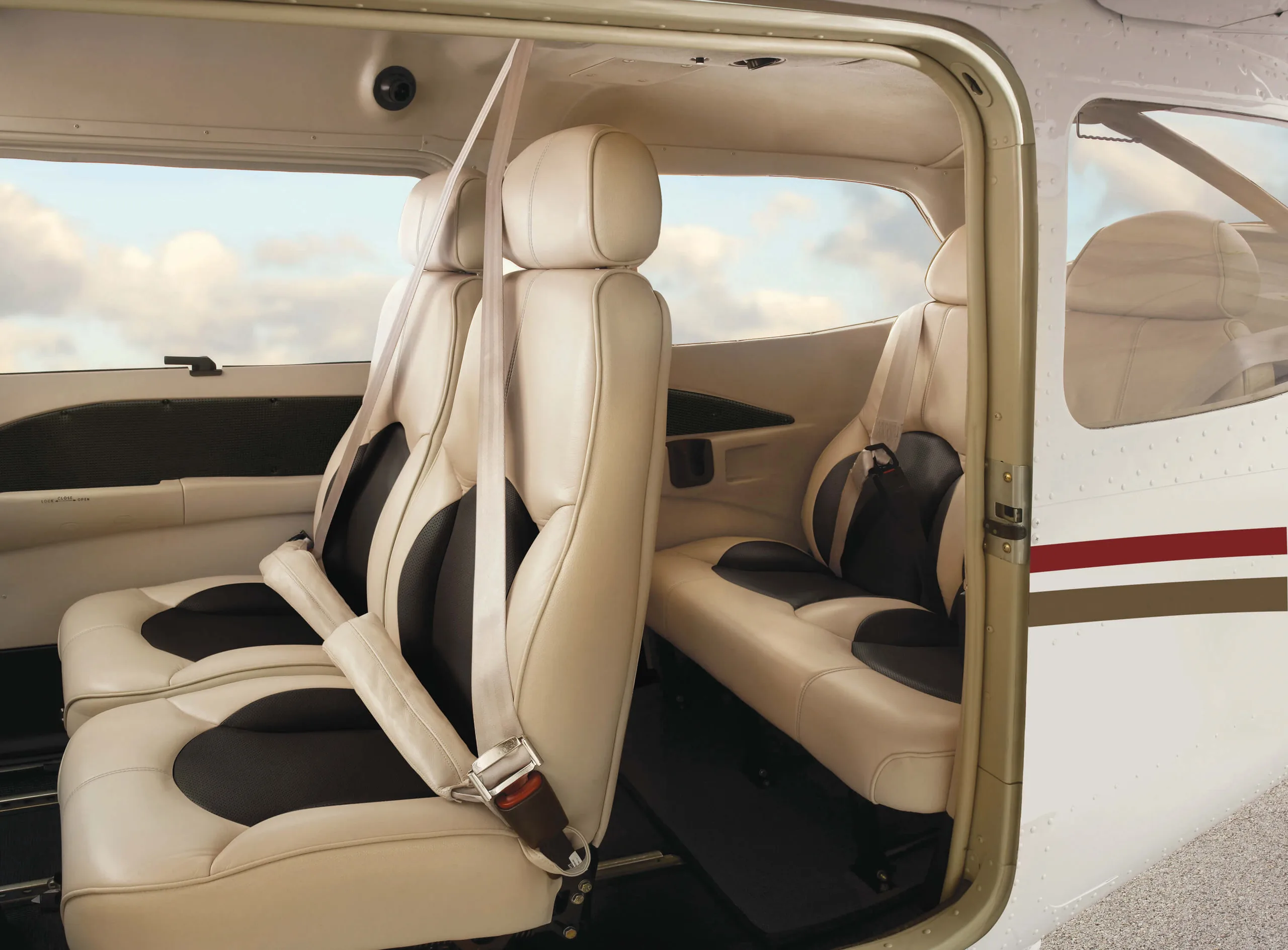 The interior of a Cessna 206 Stationair, featuring cream-colored leather seats with black accents and seatbelts.