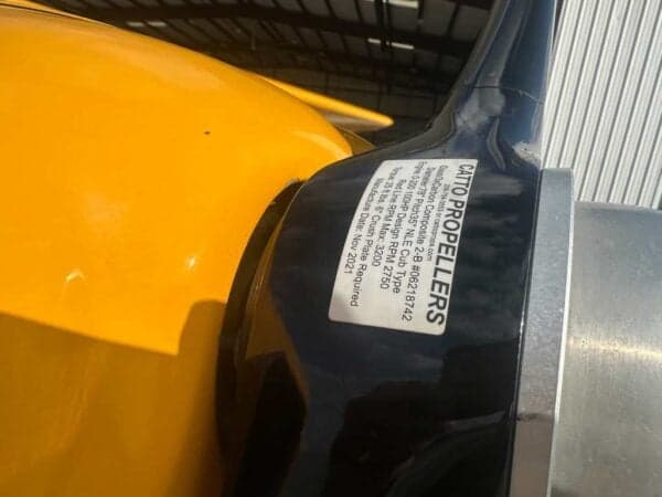 Close-up of a black propeller blade with a 'CATTO PROPELLERS' label, on a yellow aircraft.