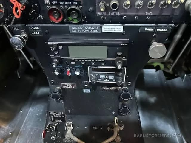 A close-up view of the avionics stack and lower control panel in an aircraft cockpit, showing radios and switches.