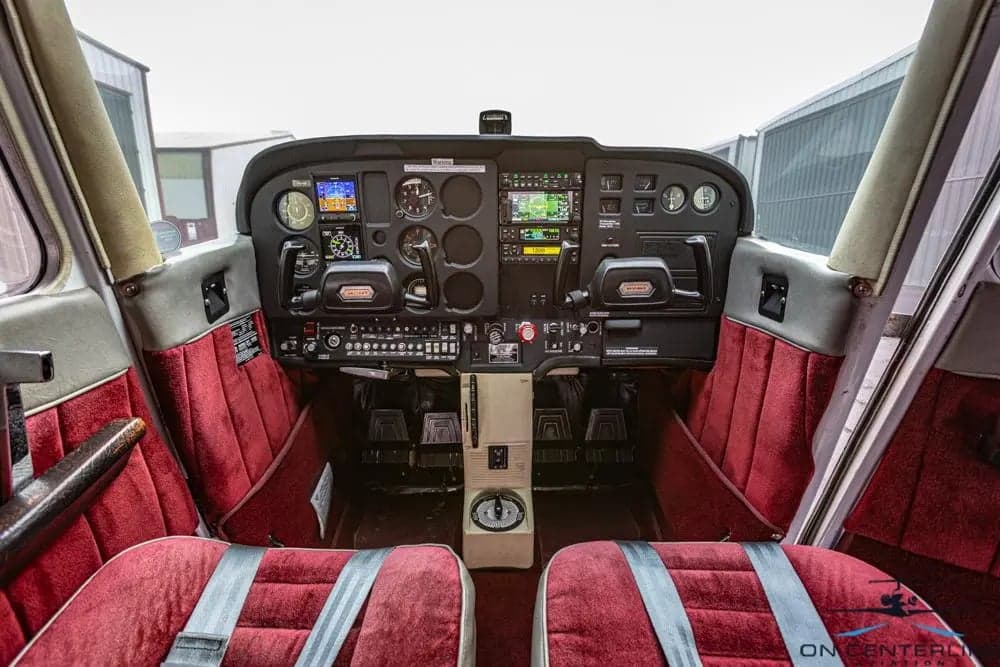 View of the Cessna 172 Skyhawk cockpit with red seats and instrument panel.