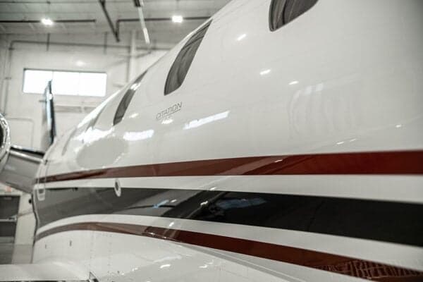 A close-up of the fuselage of a Citation jet with a white and red paint scheme.