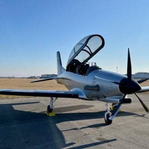 A silver CEAD aircraft sits on the tarmac with the canopy open.