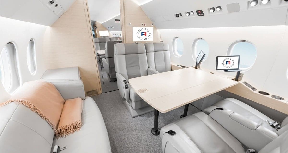 Aircraft interior with light gray seats and a table.