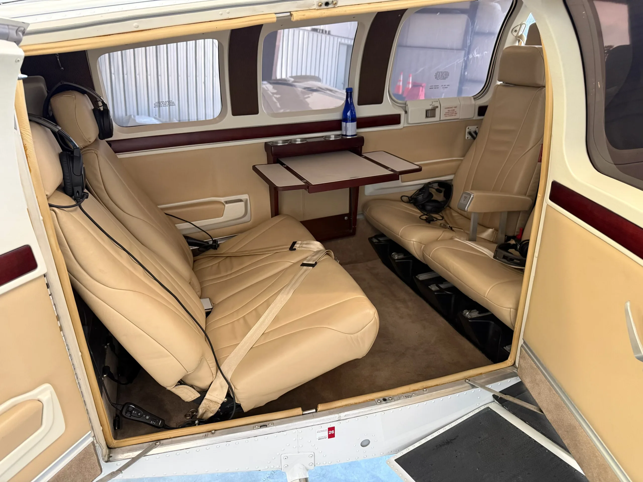 The tan leather interior cabin of a Beechcraft Bonanza with a small table and headphones.