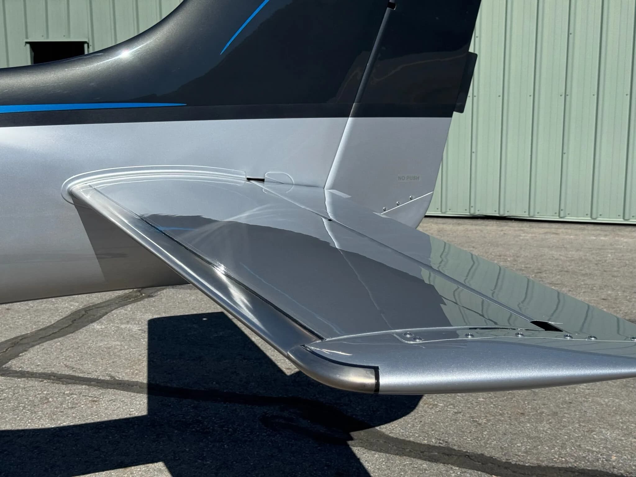 A close-up view of the horizontal stabilizer and tail section of a silver and black Cirrus SR22T aircraft.