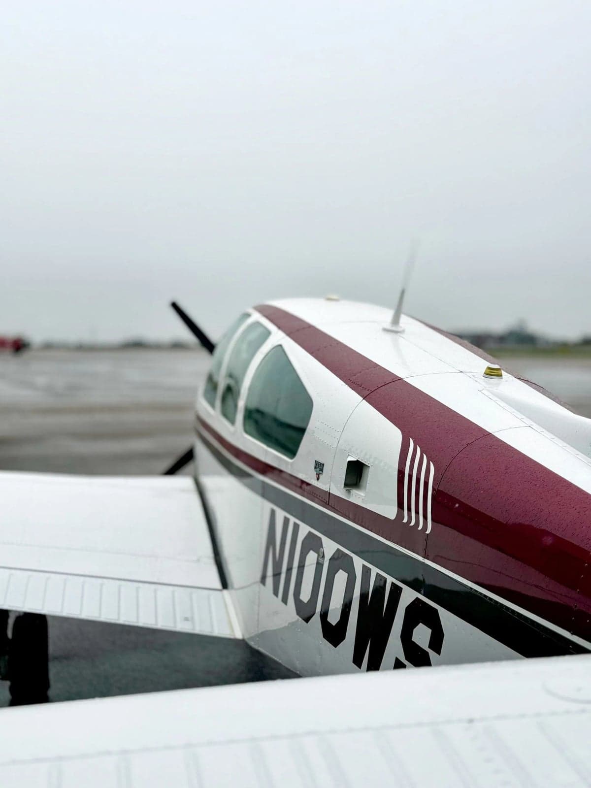 N100WS Bonanza aircraft parked in front of a hangar with a red door.