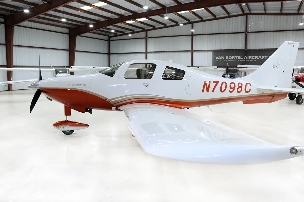 A side view of a white and red Columbia 400 aircraft with registration N7098C in a hangar.