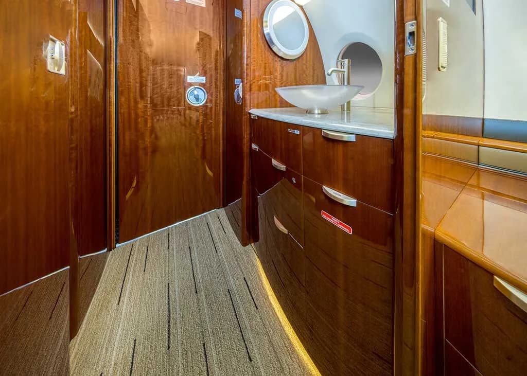 A close-up view of the aircraft's lavatory or galley area with a modern sink and polished wood cabinetry.