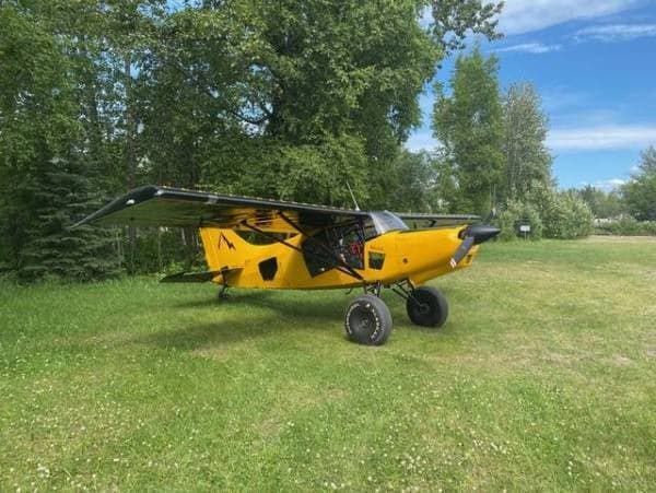 A yellow Maule aircraft is parked on a grassy field.