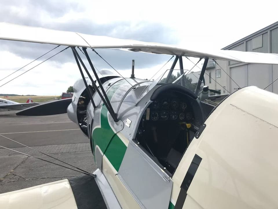 Side view of the biplane aircraft on the tarmac with other aircraft in the background.
