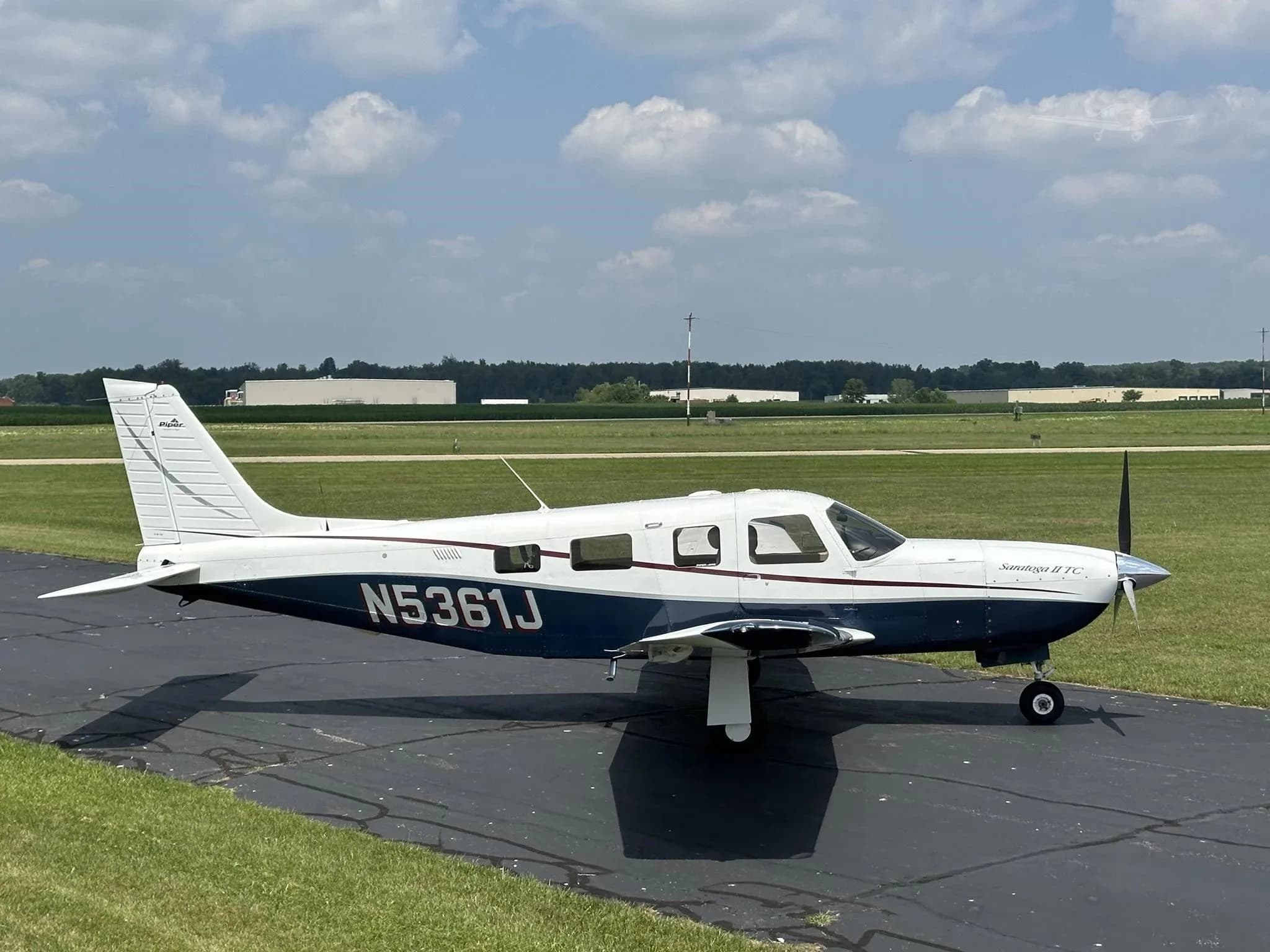 A side view of the white and blue Piper Saratoga II TC (N5361J) parked on an airfield.
