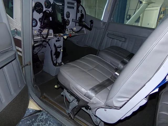 The gray leather cabin seats and a partial view of the cockpit of a Cessna 182, looking forward from the rear.