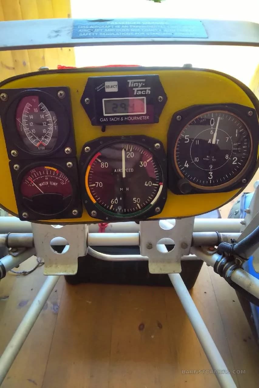 A close-up of a yellow instrument panel with an airspeed indicator, altimeter, and other gauges.