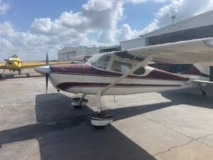 A Cessna 170A aircraft with a maroon and white paint scheme parked on the tarmac.
