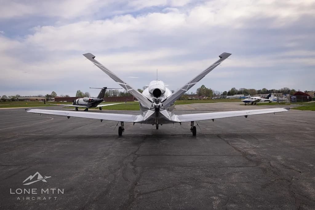 A rear view of a white and black Cirrus Vision Jet (N63KL) with its V-tail, parked on an asphalt apron.