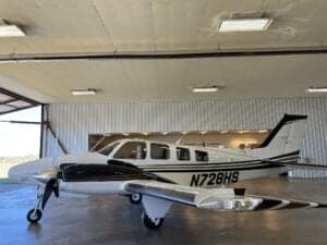 N728HS aircraft parked inside a hangar with the door open.
